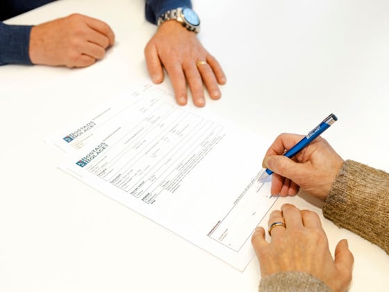 Två personer som sitter vid ett bord och skriver under ett dokument.