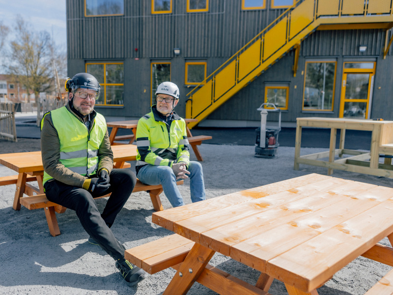 Några män sitter på träbänkar.