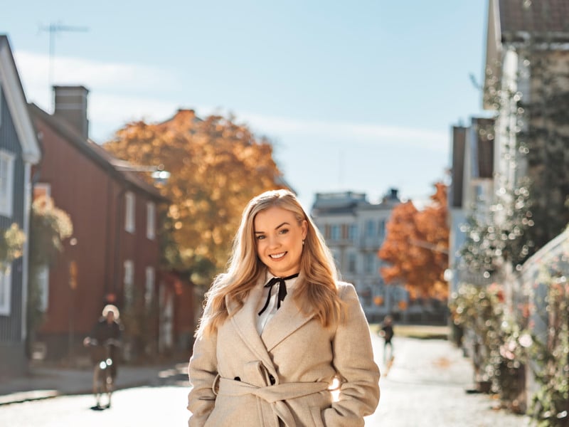 En kvinna står på en kullerstensgata.