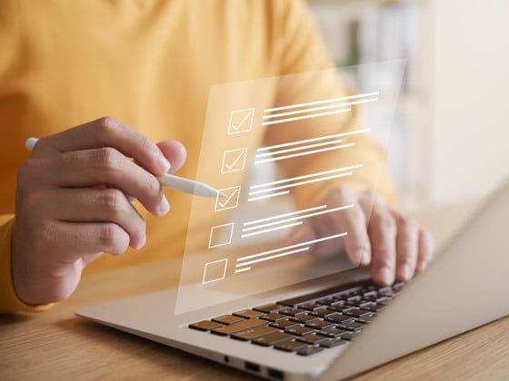 En person som använder en bärbar dator med en checklista på skärmen.