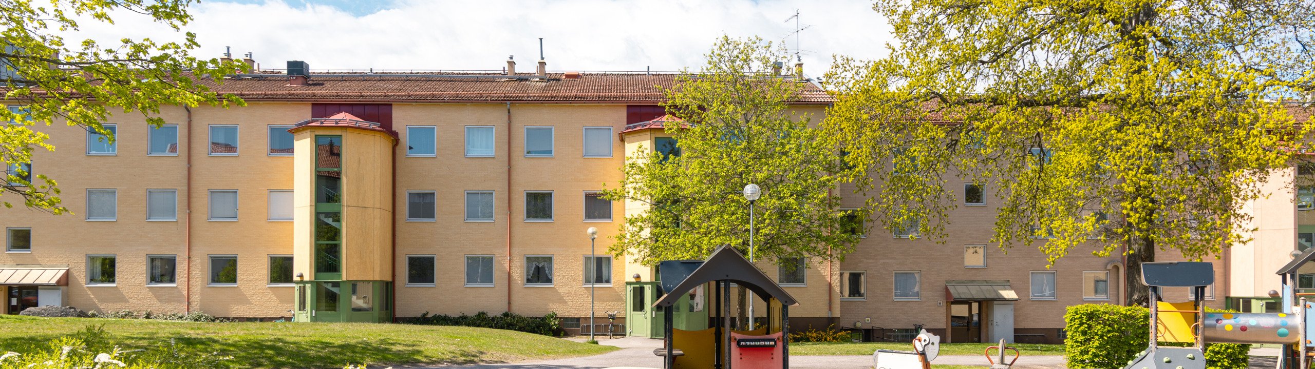 En lekplats framför ett flerfamiljshus.