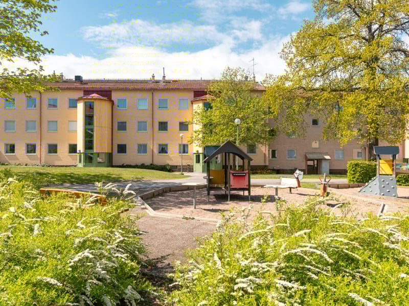 En lekplats framför ett flerfamiljshus.