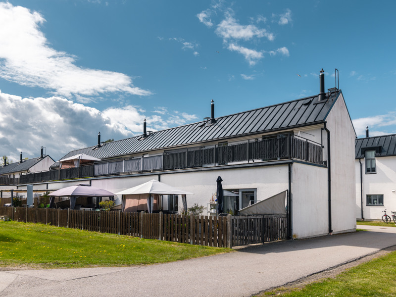 Ett vitt hus med svart tak och ett staket.