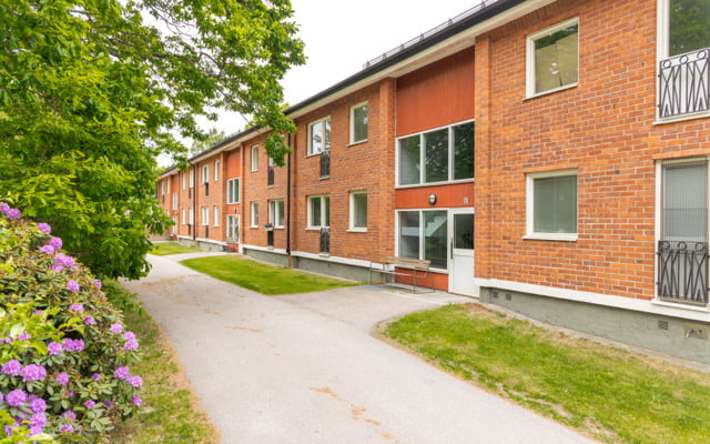 Ett hyreshus i tegel med en gångväg som leder till det.