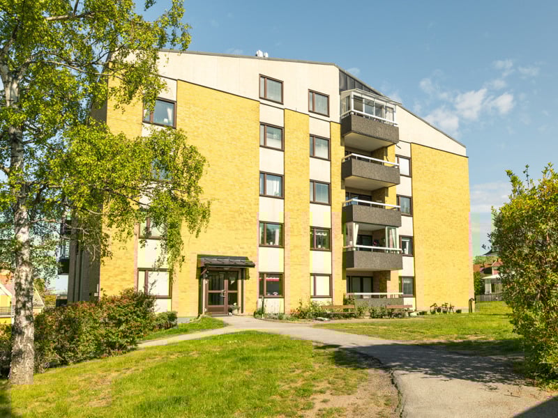 Ett gult hyreshus med en gångväg framför sig.