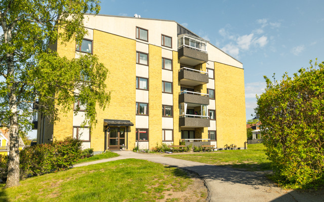 Ett gult hyreshus med en gångväg framför sig.