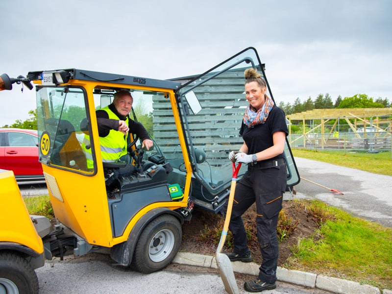 En kvinna står bredvid ett gult fordon.