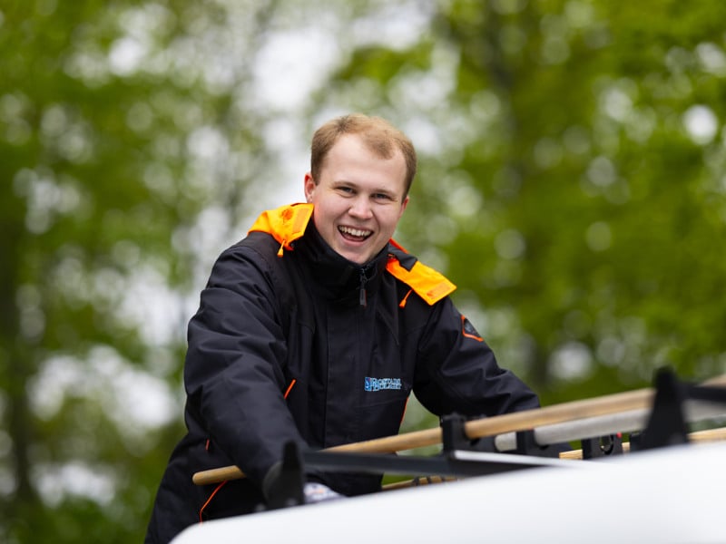 En man i svart och gul jacka ler mot kameran.