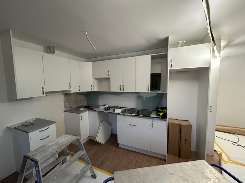 Ett kök med vita skåp och en stege.