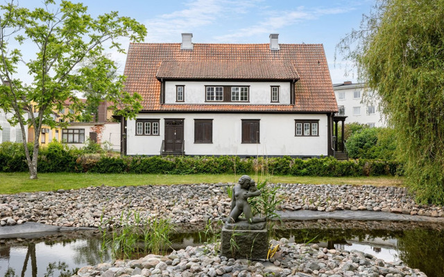 Ett hus med en damm framför sig.