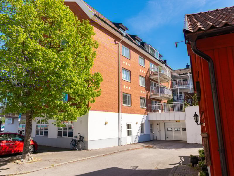 En röd bil parkerad framför en hög byggnad.