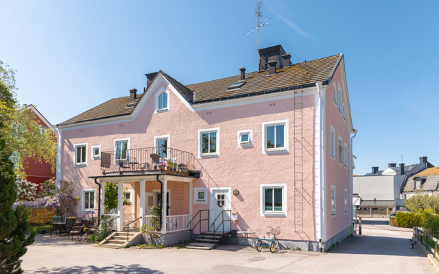 Ett rosa hus med balkong och trappa.