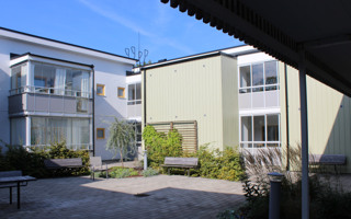 En innergård med en bänk och en byggnad i bakgrunden.