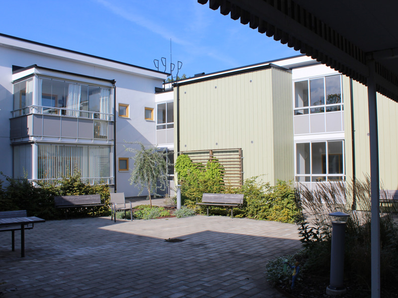 En innergård med en bänk och en byggnad i bakgrunden.