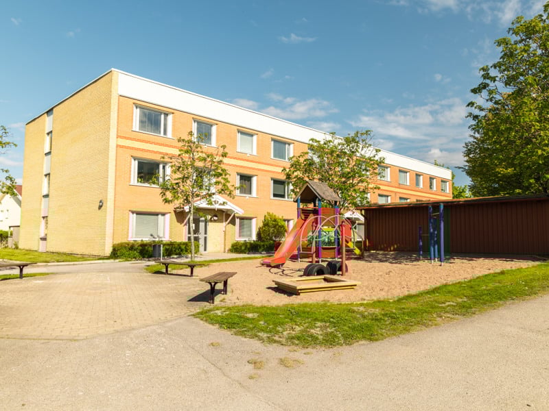 En lekplats framför ett flerfamiljshus.